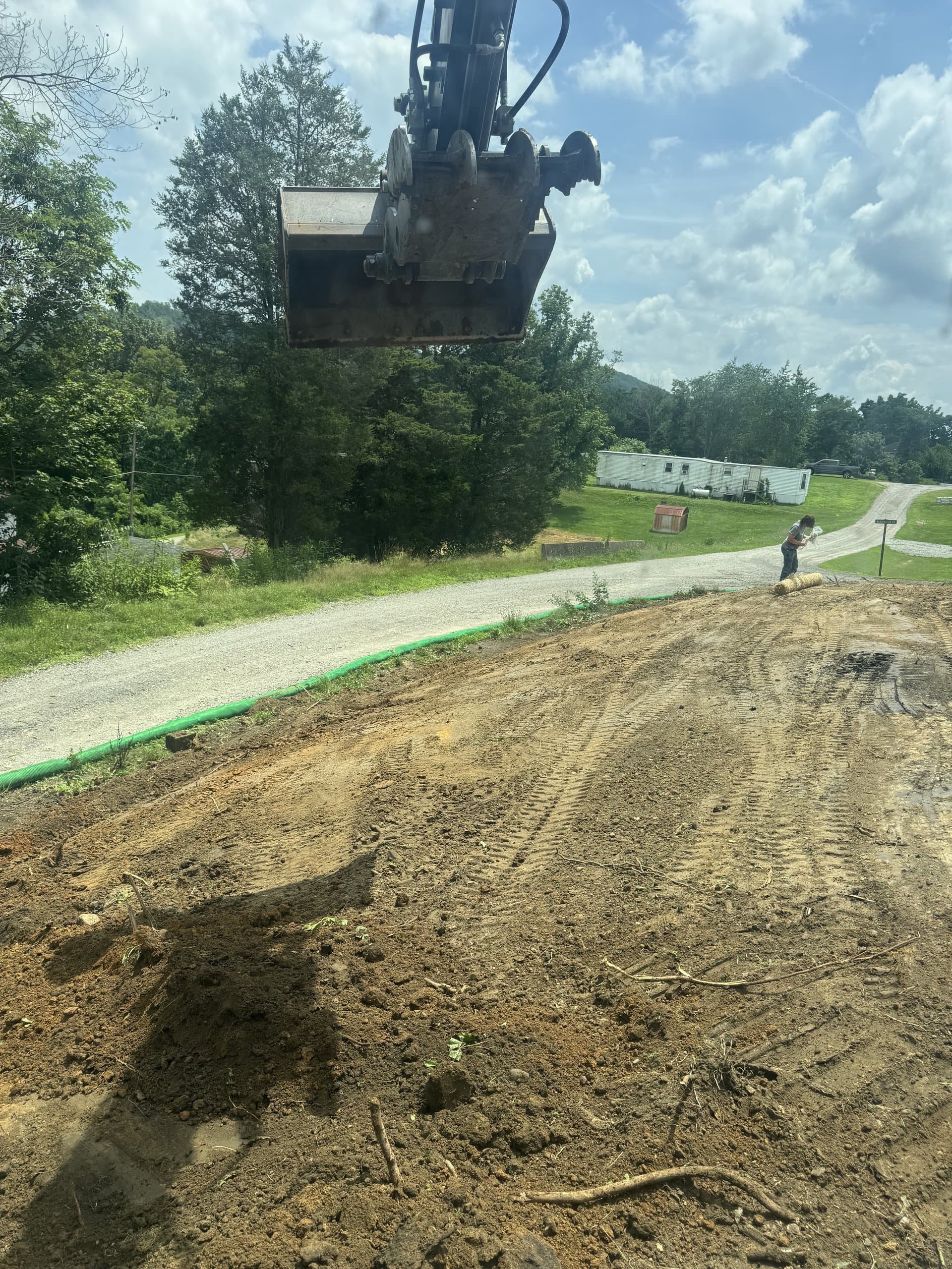 Freshly graded site pad with silt fence along the gravel driveway