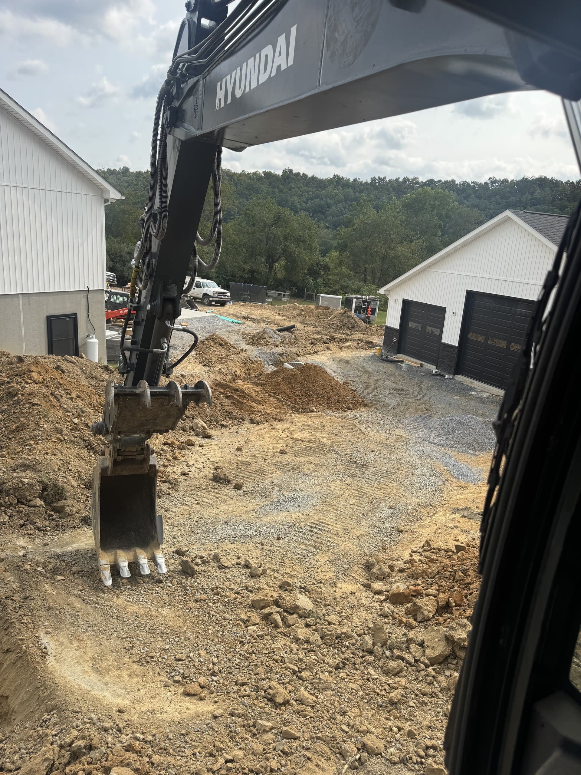 Excavator finishing a residential driveway cut next to the house