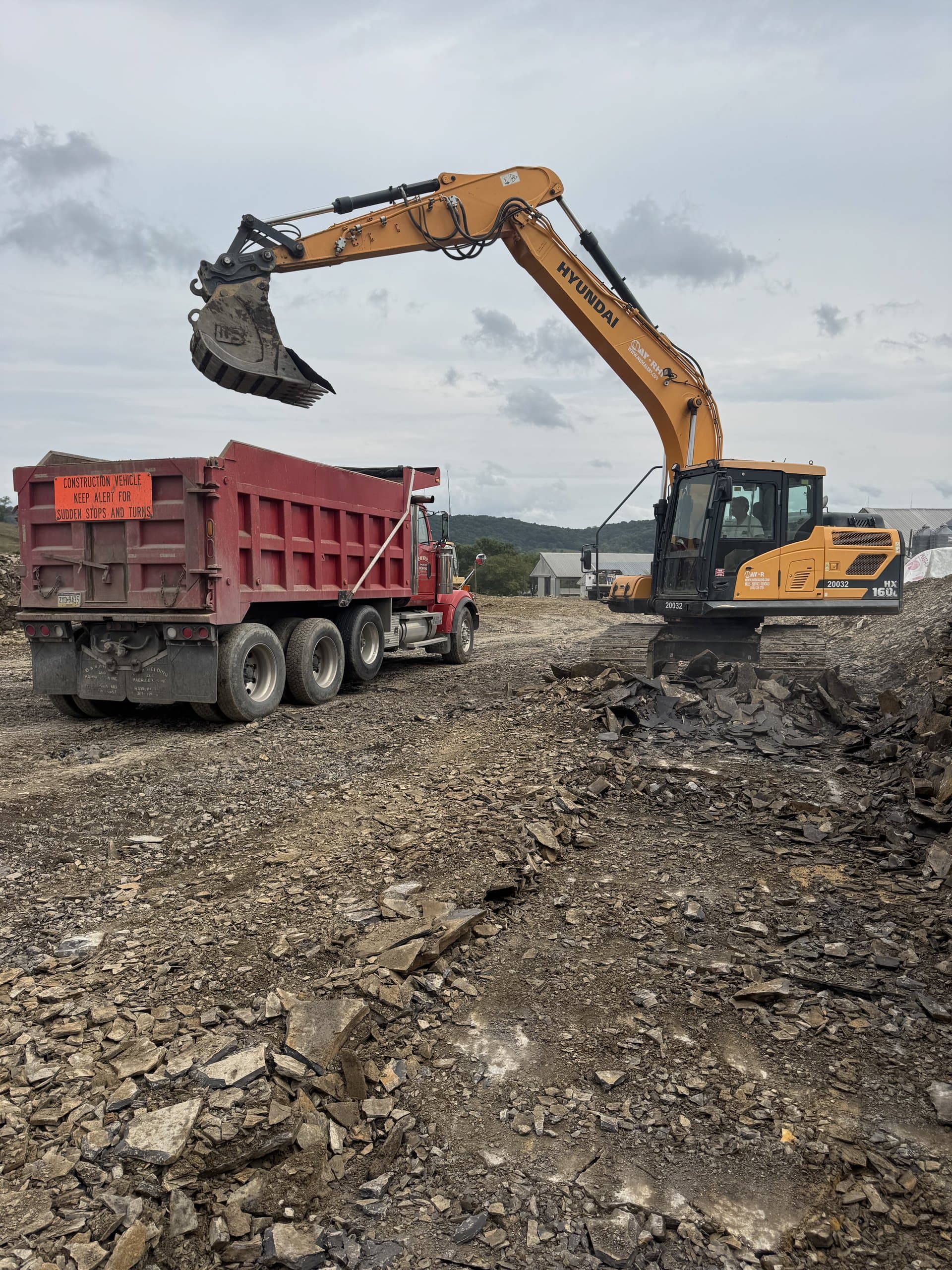 Excavator loading screened topsoil into the red EW Wise dump truck