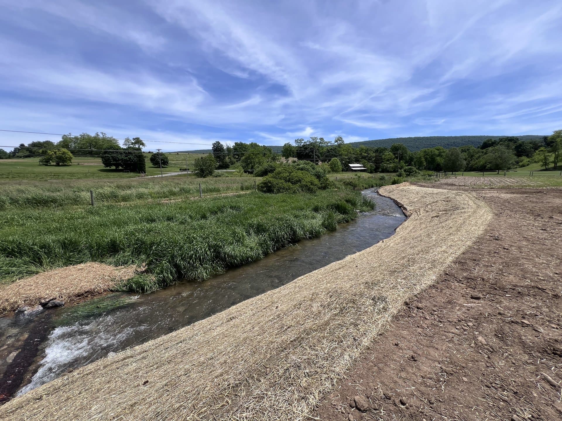 Restored curving streambank with Pennsylvania ridge line in the background
