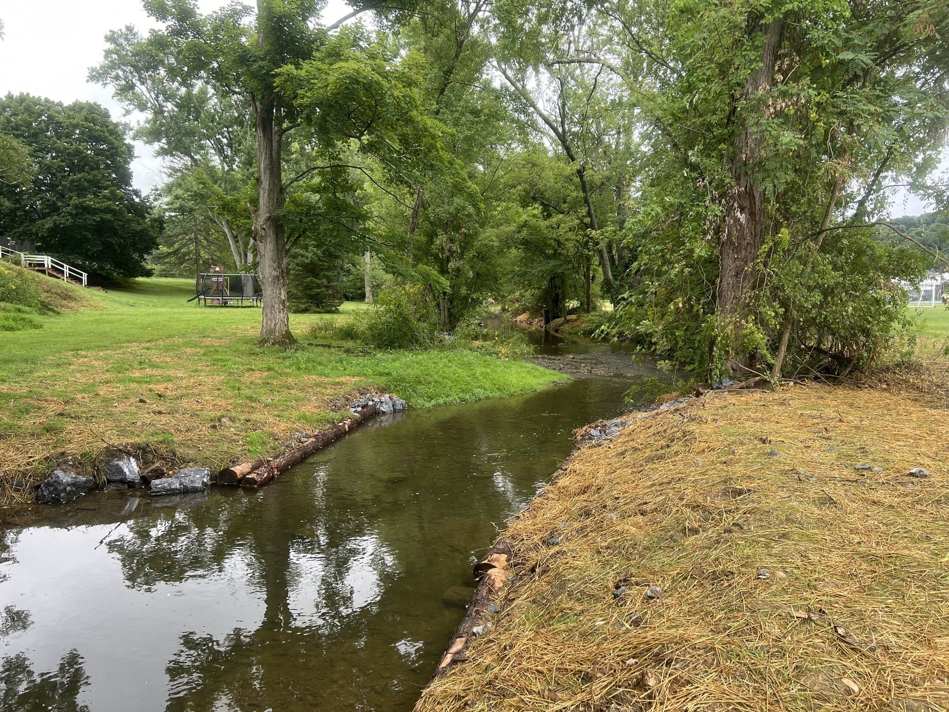 Park stream restoration with bench beside the mulched curving bank
