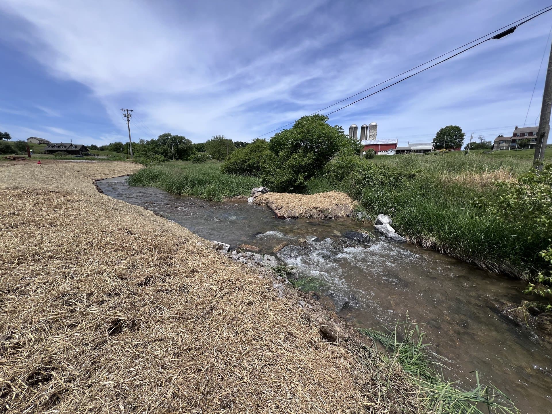 Restored stream with fresh straw mulched bank running through a community